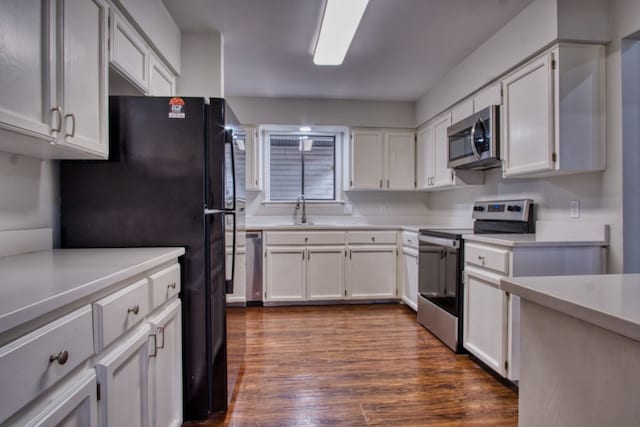 kitchen with dark hardwood / wood-style flooring, white cabinetry, sink, and stainless steel appliances