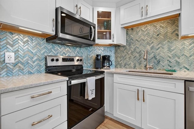 6649 Seacomber Dr Unit 807, Port Aransas, TX 78373 - kitchen with appliances with stainless steel finishes, backsplash, white cabinets, glass insert cabinets, and light stone counters