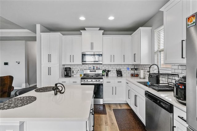 kitchen with light countertops, white cabinetry, appliances with stainless steel finishes, and decorative backsplash