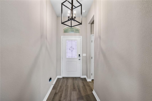 doorway to outside with baseboards, dark wood-style flooring, and a chandelier