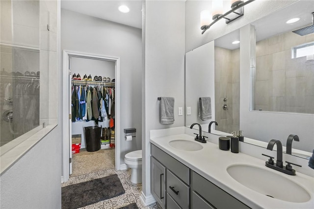 full bathroom with double vanity, tiled shower, and a sink