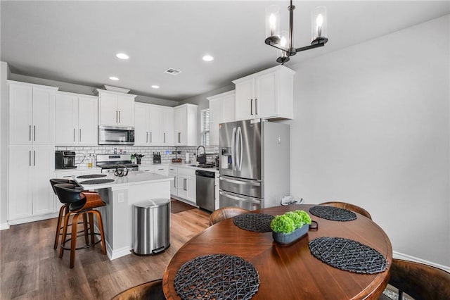 kitchen with decorative backsplash, a kitchen bar, a center island, a sink, and stainless steel appliances