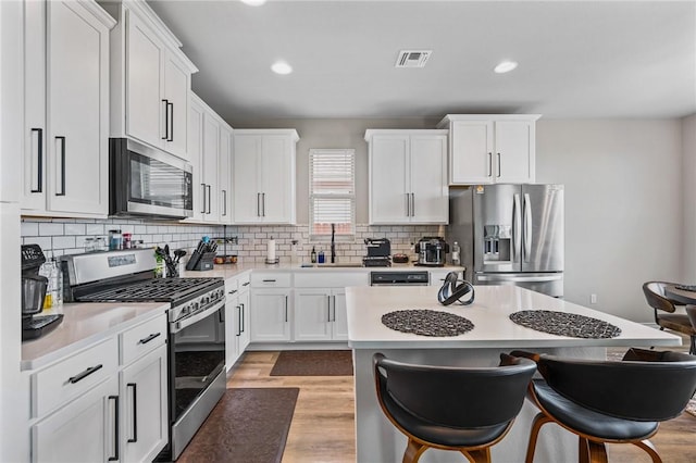 kitchen featuring a kitchen breakfast bar, visible vents, a sink, light countertops, and stainless steel appliances