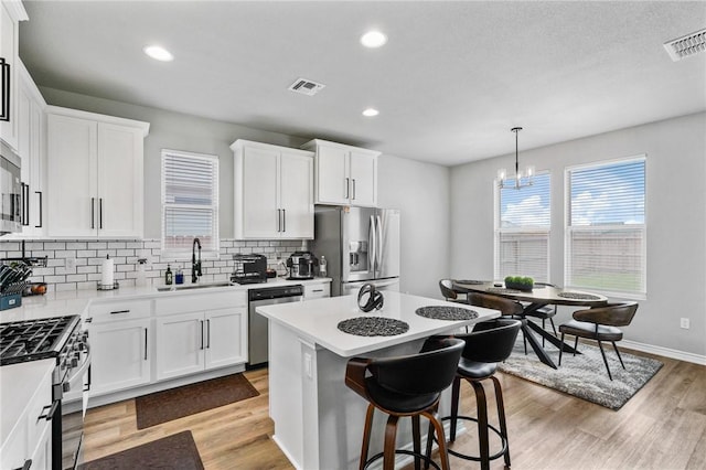 kitchen featuring visible vents, a sink, backsplash, and stainless steel appliances