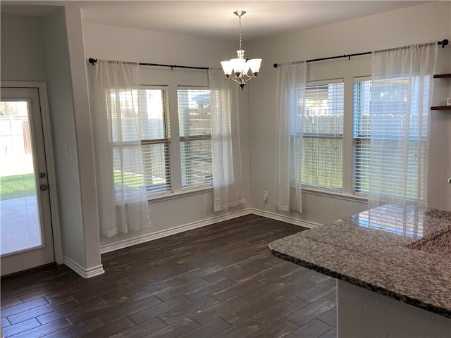 unfurnished dining area with dark wood-type flooring and an inviting chandelier