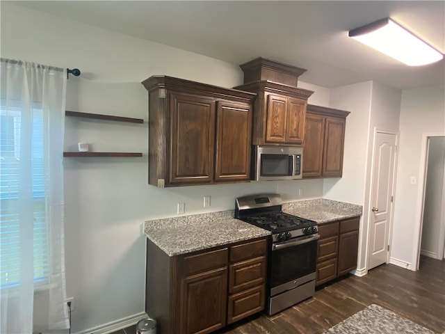 kitchen with dark brown cabinets, light stone countertops, dark wood-type flooring, and appliances with stainless steel finishes