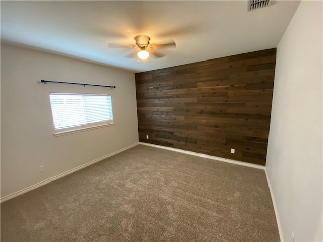 unfurnished room featuring dark carpet, ceiling fan, and wood walls