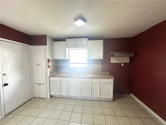 kitchen with white cabinetry, decorative backsplash, sink, and light tile patterned flooring