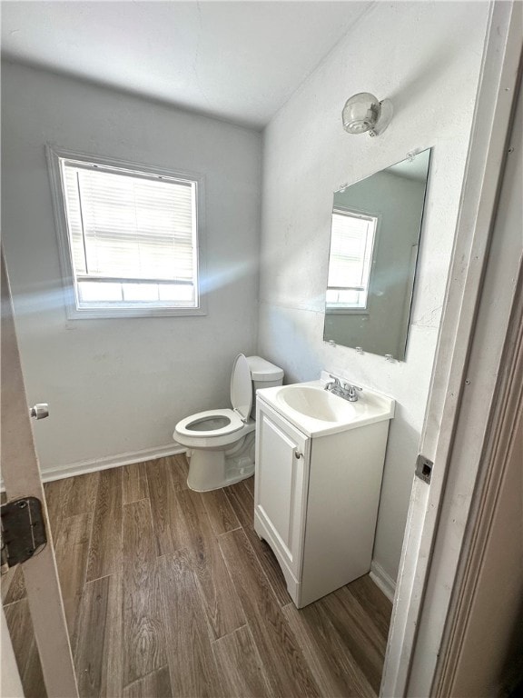 bathroom with vanity, hardwood / wood-style flooring, a healthy amount of sunlight, and toilet