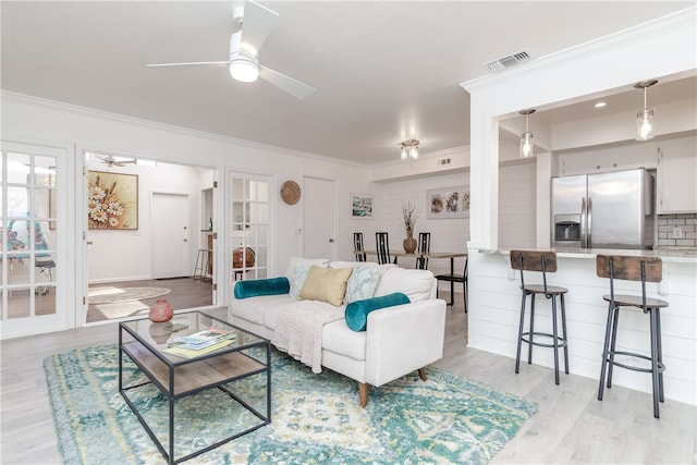 living room featuring ceiling fan, light hardwood / wood-style floors, and crown molding