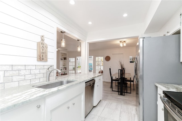 kitchen with white cabinets, hanging light fixtures, sink, and stainless steel appliances