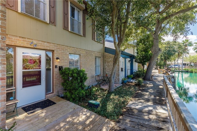 view of exterior entry with a deck with water view