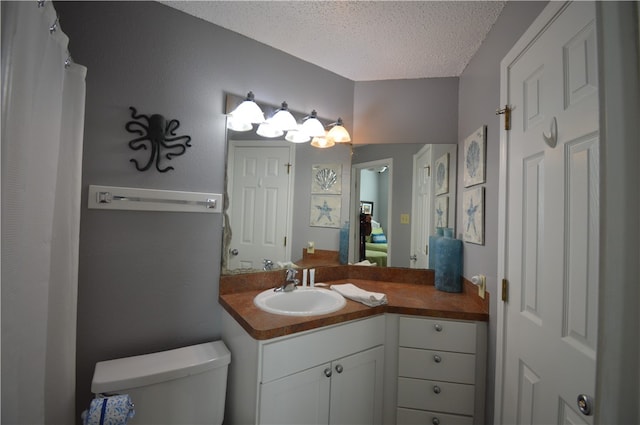 bathroom featuring vanity, a textured ceiling, and toilet