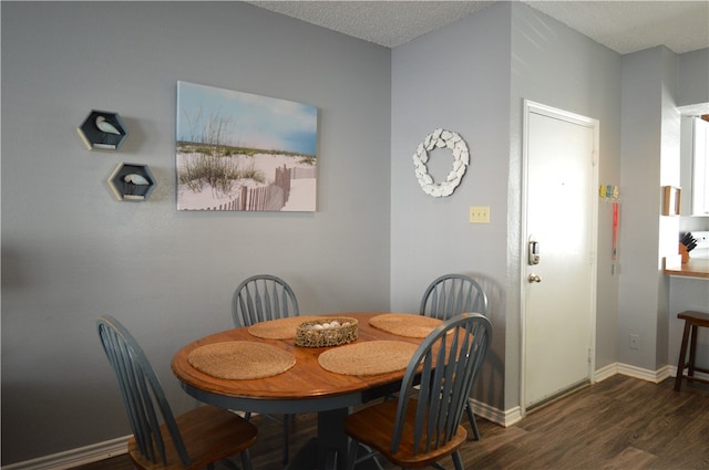 dining room featuring a textured ceiling and dark hardwood / wood-style flooring