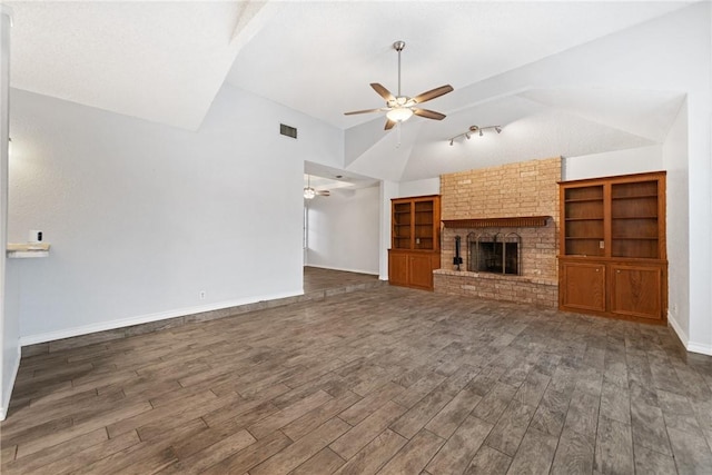 unfurnished living room featuring lofted ceiling, a brick fireplace, and dark wood-type flooring