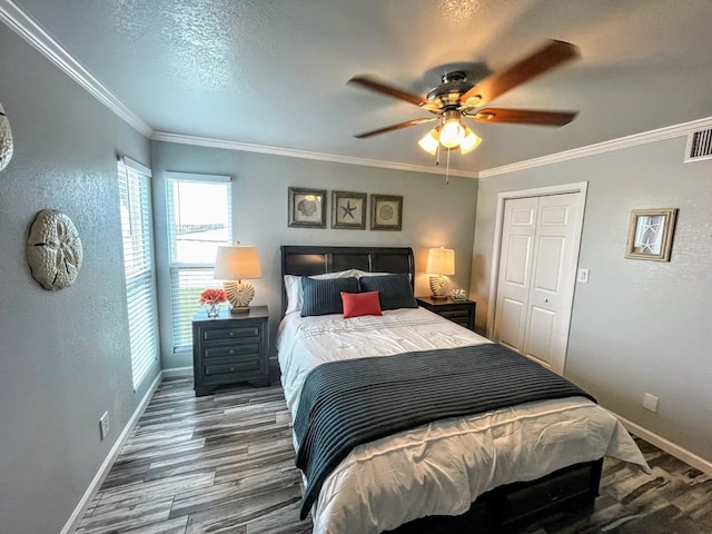 bedroom with baseboards, multiple windows, a textured wall, ornamental molding, and wood finished floors