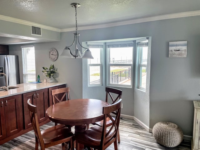 dining room with light wood-type flooring, plenty of natural light, baseboards, a chandelier, and ornamental molding
