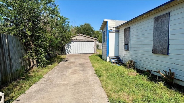 view of side of home with fence, an outbuilding, a detached garage, and entry steps