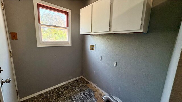 washroom featuring baseboards, washer hookup, and cabinet space