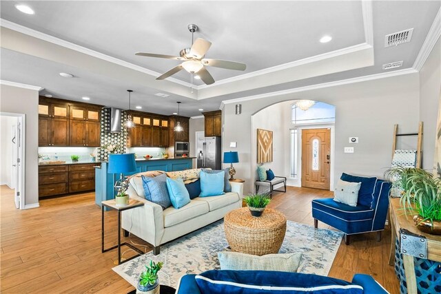 2718 Yeager Dr, Corpus Christi, TX 78410 - living area with a tray ceiling, arched walkways, light wood-type flooring, a ceiling fan, and crown molding