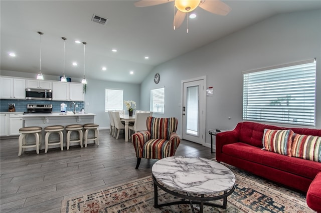 living room with dark hardwood / wood-style floors, ceiling fan, plenty of natural light, and lofted ceiling