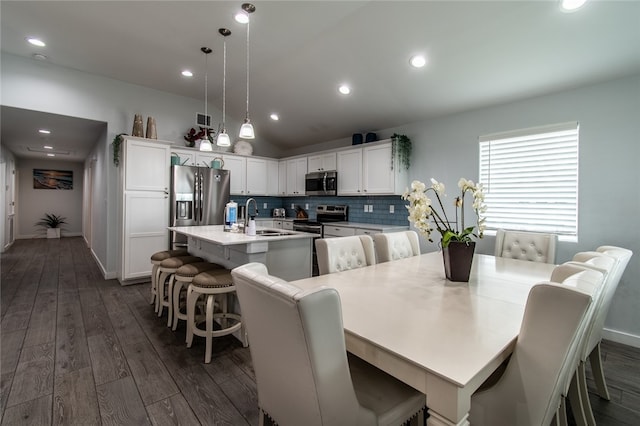 dining area featuring dark wood-type flooring, sink, and vaulted ceiling