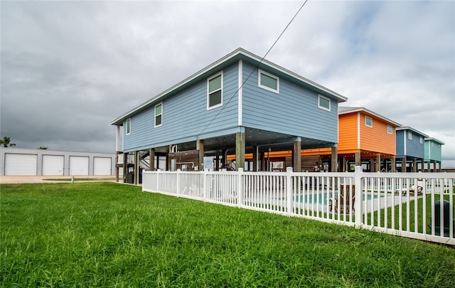 rear view of property featuring a garage, a lawn, and a fenced in pool