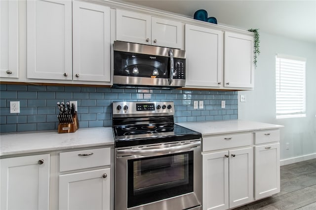 kitchen with light stone counters, white cabinetry, appliances with stainless steel finishes, decorative backsplash, and hardwood / wood-style flooring