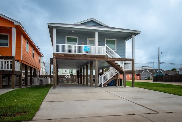 coastal inspired home with a porch, a front yard, and a carport