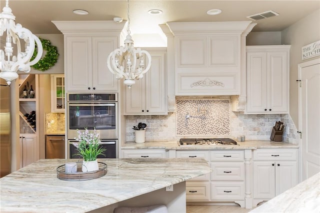 5030 S Oso Pkwy, Corpus Christi, TX 78413 - kitchen with appliances with stainless steel finishes, a chandelier, light stone counters, and decorative backsplash