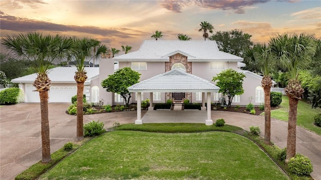 8018 Saint Laurent Dr, Corpus Christi, TX 78414 - view of front facade with curved driveway, a tiled roof, stucco siding, and a yard
