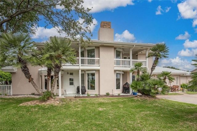 8018 Saint Laurent Dr, Corpus Christi, TX 78414 - rear view of property featuring a chimney, a yard, stucco siding, and a balcony