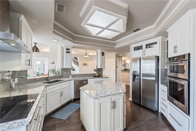 8018 Saint Laurent Dr, Corpus Christi, TX 78414 - kitchen featuring appliances with stainless steel finishes, wall chimney range hood, a tray ceiling, a sink, and backsplash