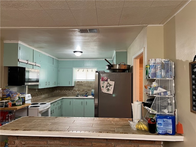 kitchen with stainless steel appliances, kitchen peninsula, decorative backsplash, sink, and crown molding