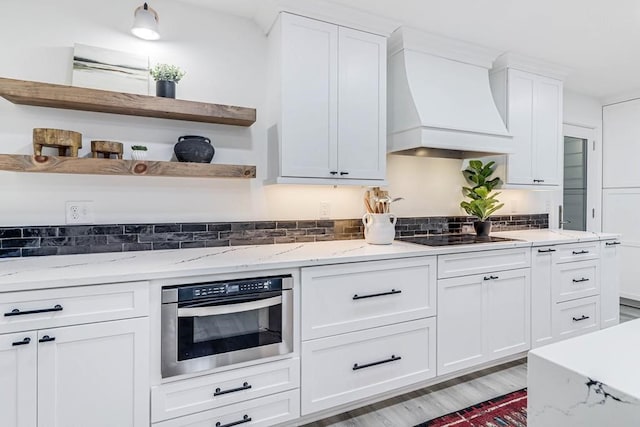 1895 Bay Shore Dr, Rockport, TX 78382 - kitchen featuring white cabinets, open shelves, black electric cooktop, premium range hood, and stainless steel oven