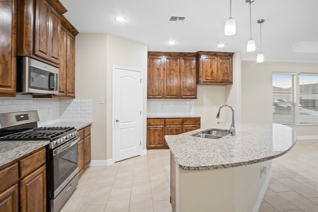 kitchen with a center island with sink, appliances with stainless steel finishes, sink, and backsplash