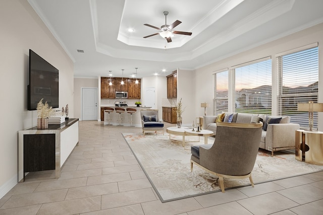 living room featuring ornamental molding, ceiling fan, a raised ceiling, and light tile patterned floors