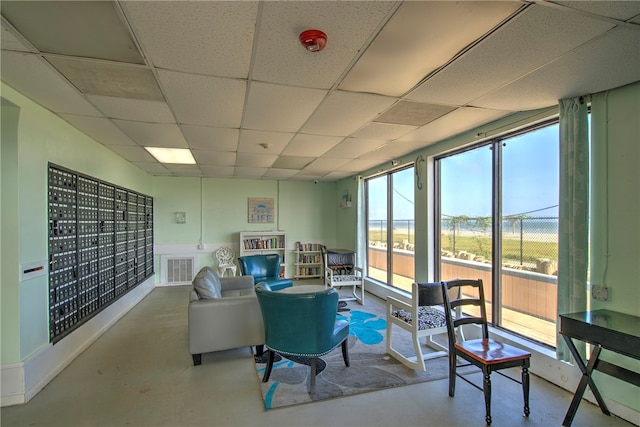 living room featuring a wealth of natural light, concrete floors, and a drop ceiling