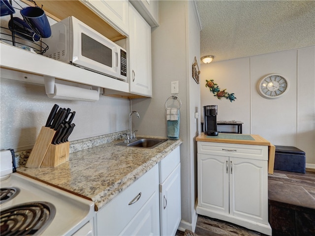 kitchen with sink, dark hardwood / wood-style floors, a textured ceiling, white appliances, and white cabinets