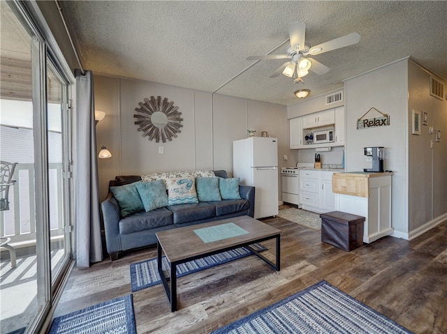 living room with dark wood-type flooring, a textured ceiling, and ceiling fan