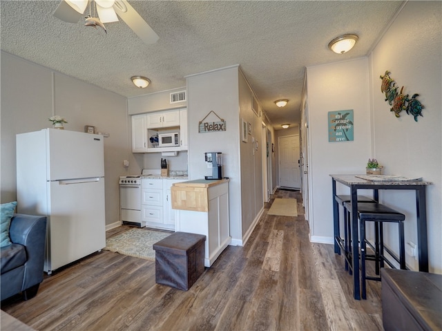 kitchen featuring white cabinetry, a textured ceiling, dark hardwood / wood-style floors, and white appliances