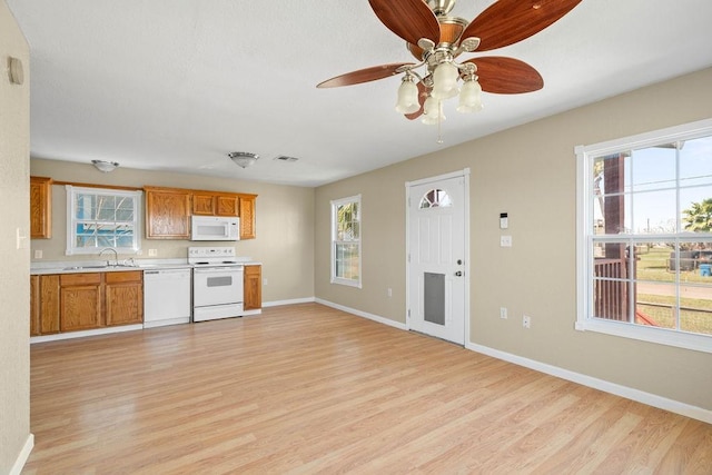 kitchen featuring light wood-style floors, white appliances, light countertops, and a sink