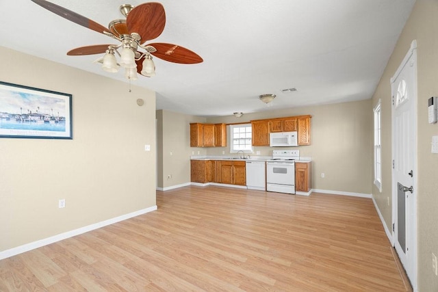 kitchen with white appliances, brown cabinetry, light countertops, light wood-style floors, and a sink