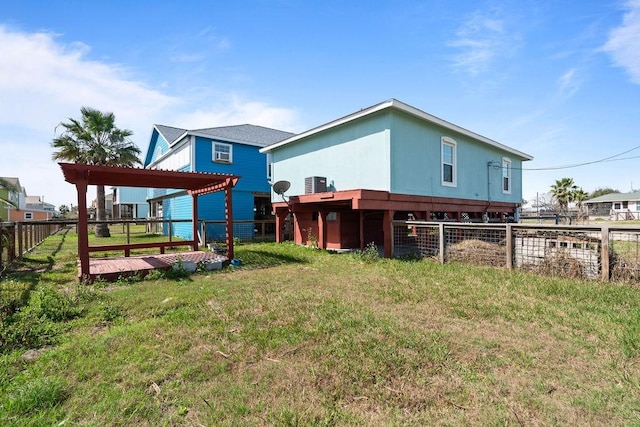 rear view of property with central AC unit, a lawn, and fence