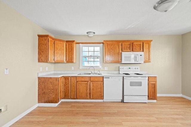 kitchen with light wood-style flooring, white appliances, a sink, light countertops, and brown cabinets