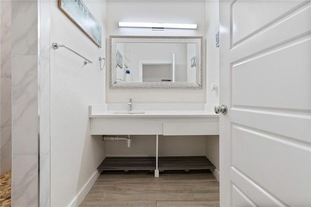 bathroom with vanity, wood finished floors, baseboards, and a shower