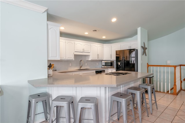 kitchen featuring light tile patterned floors, black fridge with ice dispenser, a breakfast bar, and white cabinets