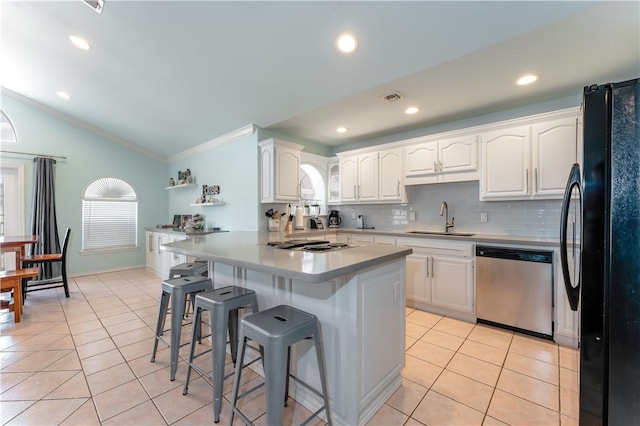 103 E Palmetto Dr Unit B, South Padre Island, TX 78597 - kitchen featuring stainless steel appliances, a kitchen bar, vaulted ceiling, ornamental molding, and light tile patterned floors