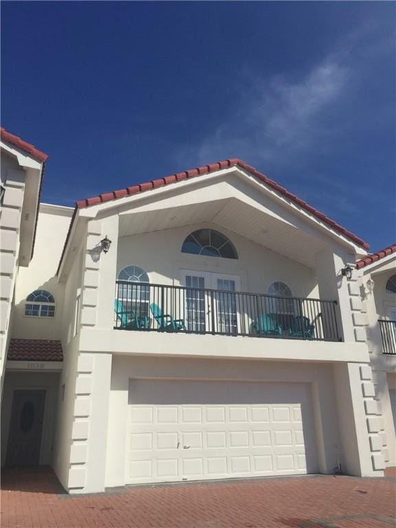 103 E Palmetto Dr Unit B, South Padre Island, TX 78597 - view of front of property with a tile roof, stucco siding, a balcony, a garage, and decorative driveway