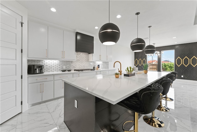 kitchen with white cabinets, a large island, a breakfast bar, light stone countertops, and pendant lighting